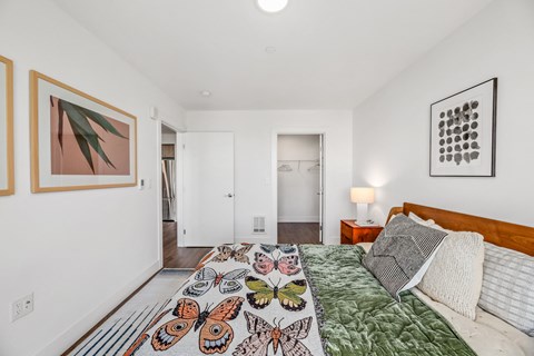 a bedroom with white walls and a bed with a colorful comforter