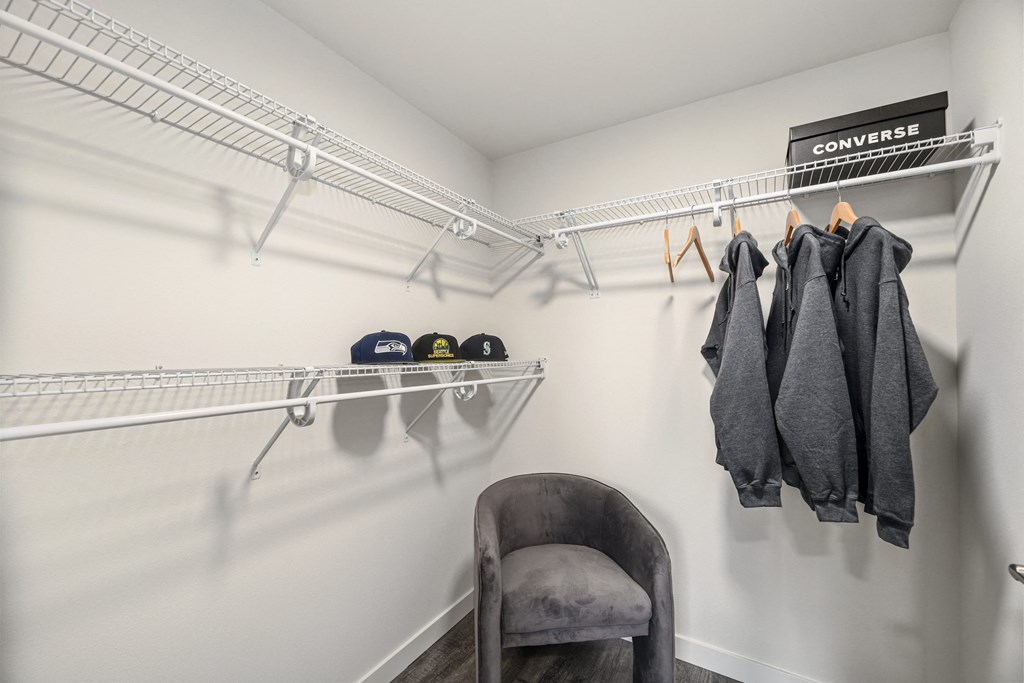 a spacious closet with a coat rack and a chair
