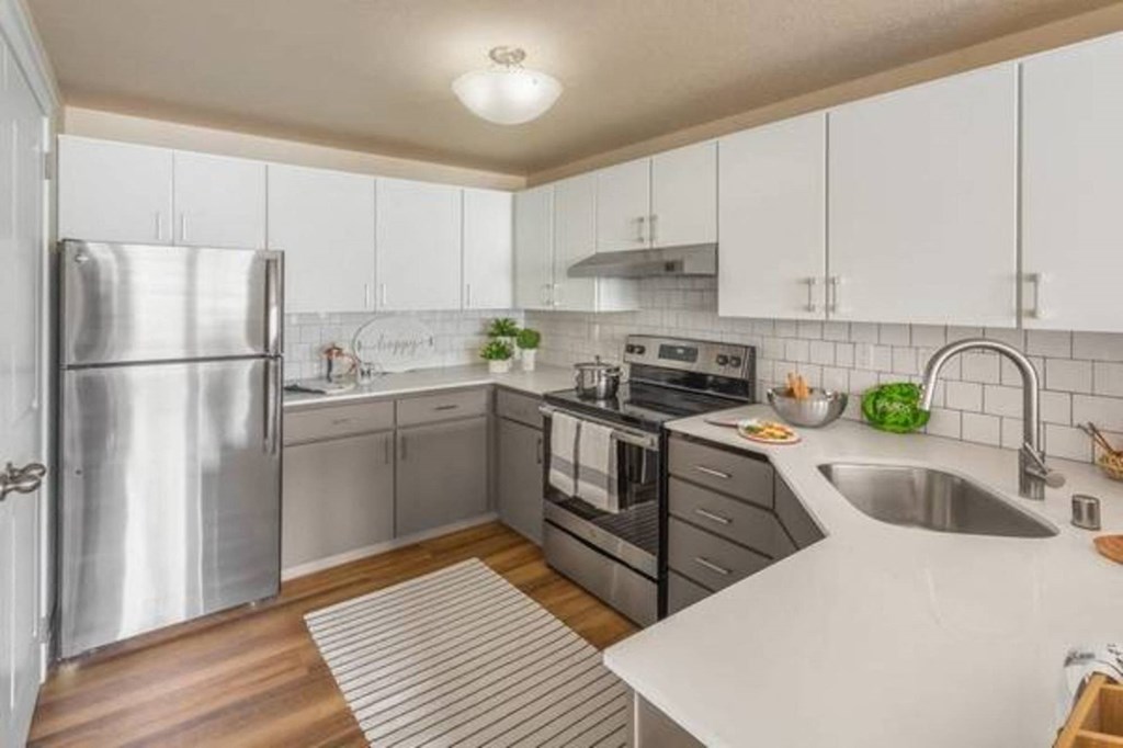 A kitchen with a stainless steel refrigerator and white cabinets.