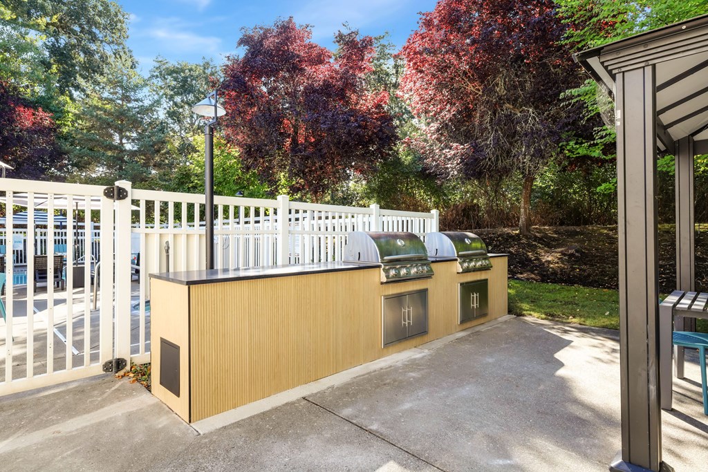 A white fence surrounds a small building with a brown roof.