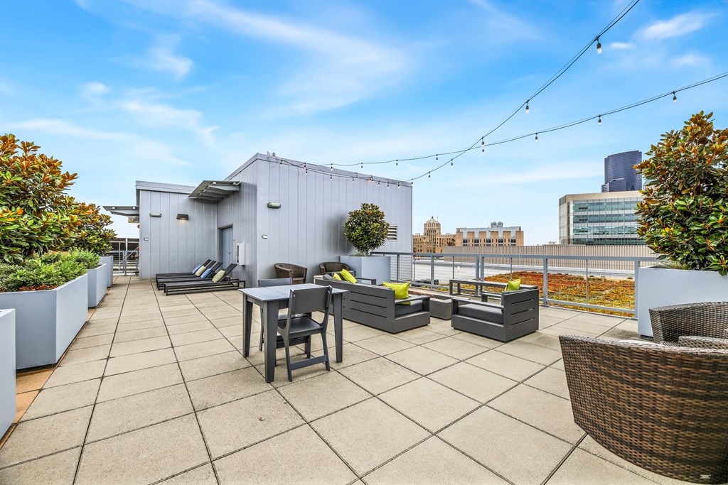 a rooftop patio with tables and chairs and a city in the background