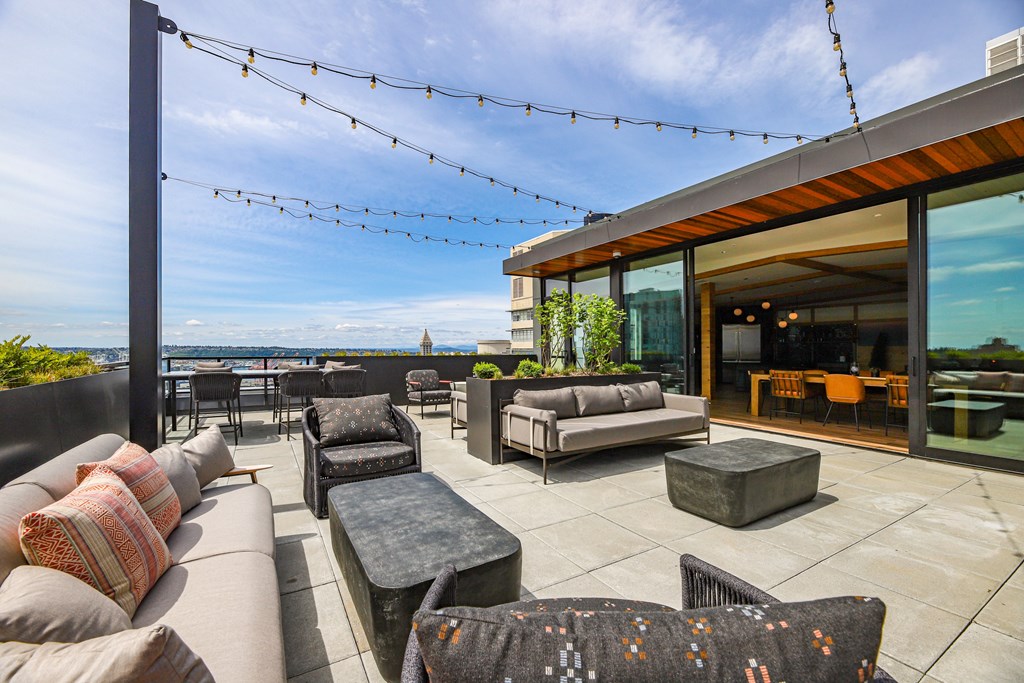 A patio with a couch, chairs, and a table with a view of the ocean.