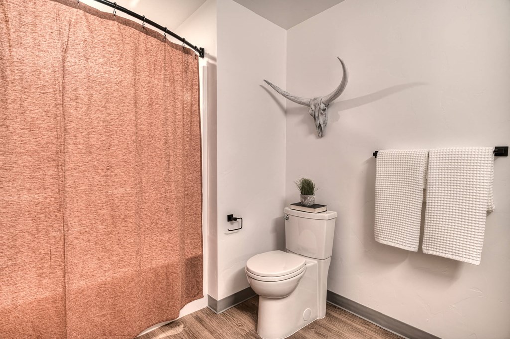 a bathroom with a toilet and a shower curtain and a deer skull on the wall