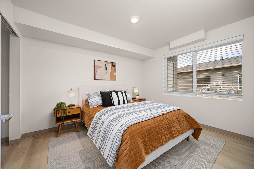 A bedroom with a bed, nightstand, and window.
