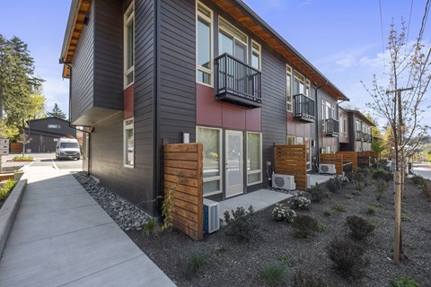 A modern house with a balcony and a small garden in front.
