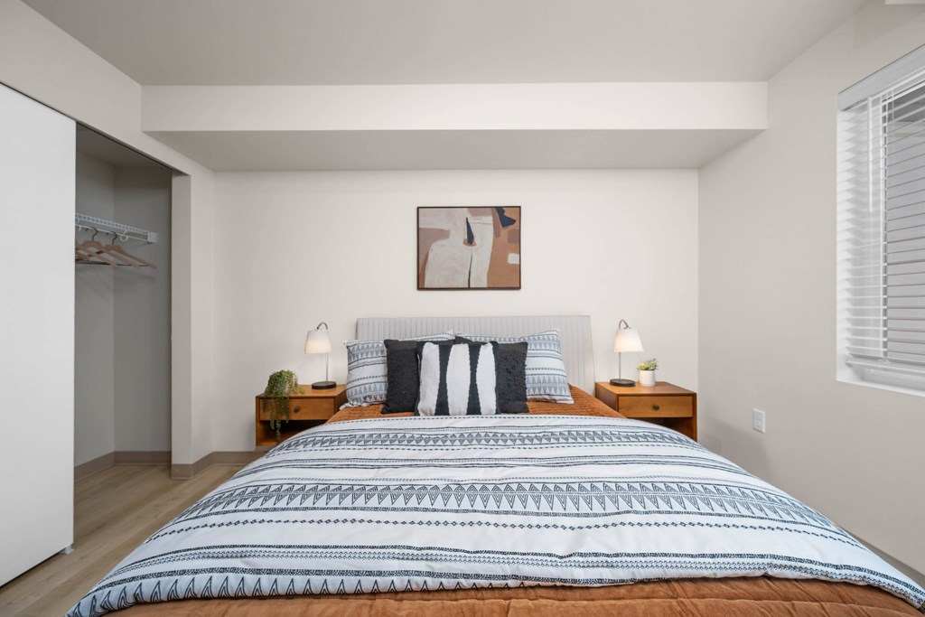 A bedroom with a large bed and two nightstands.