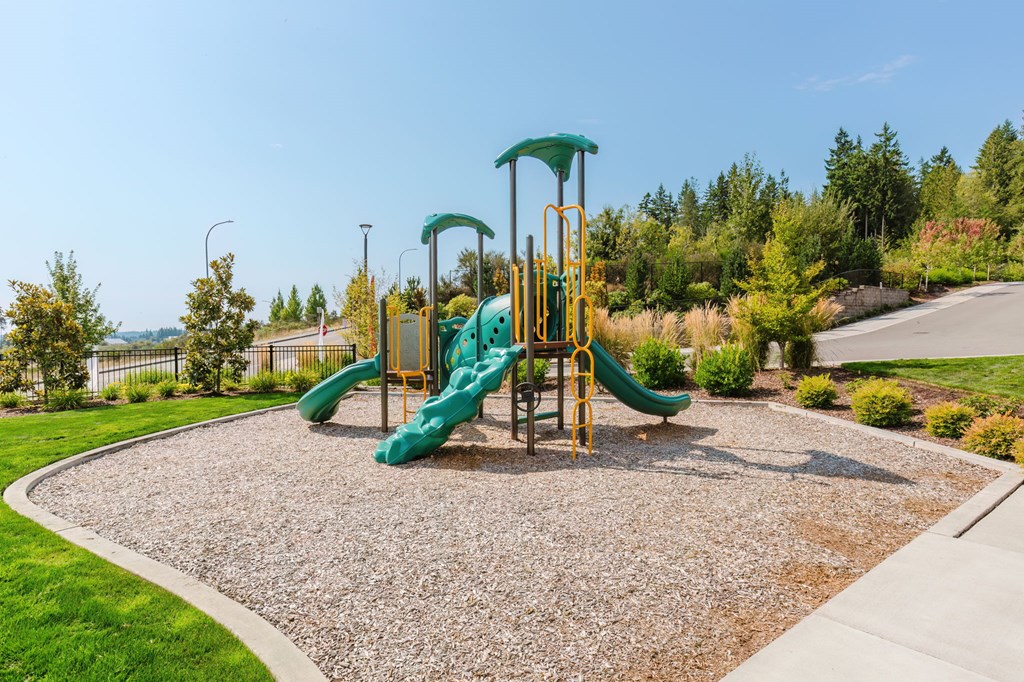 A playground with a green slide and yellow safety bars.