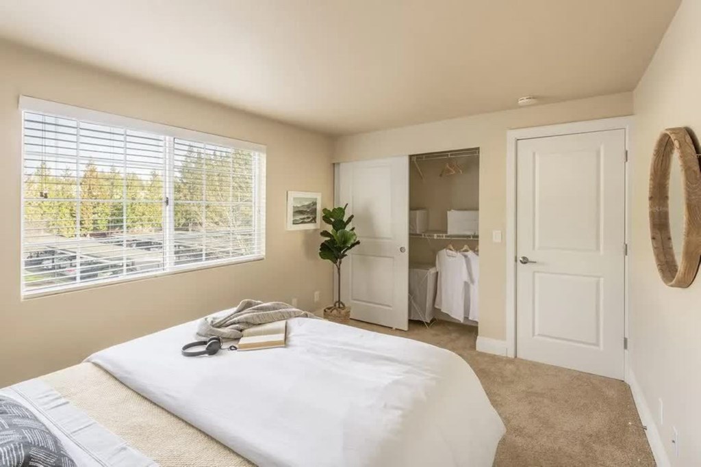 A bedroom with a large bed and a window with blinds.