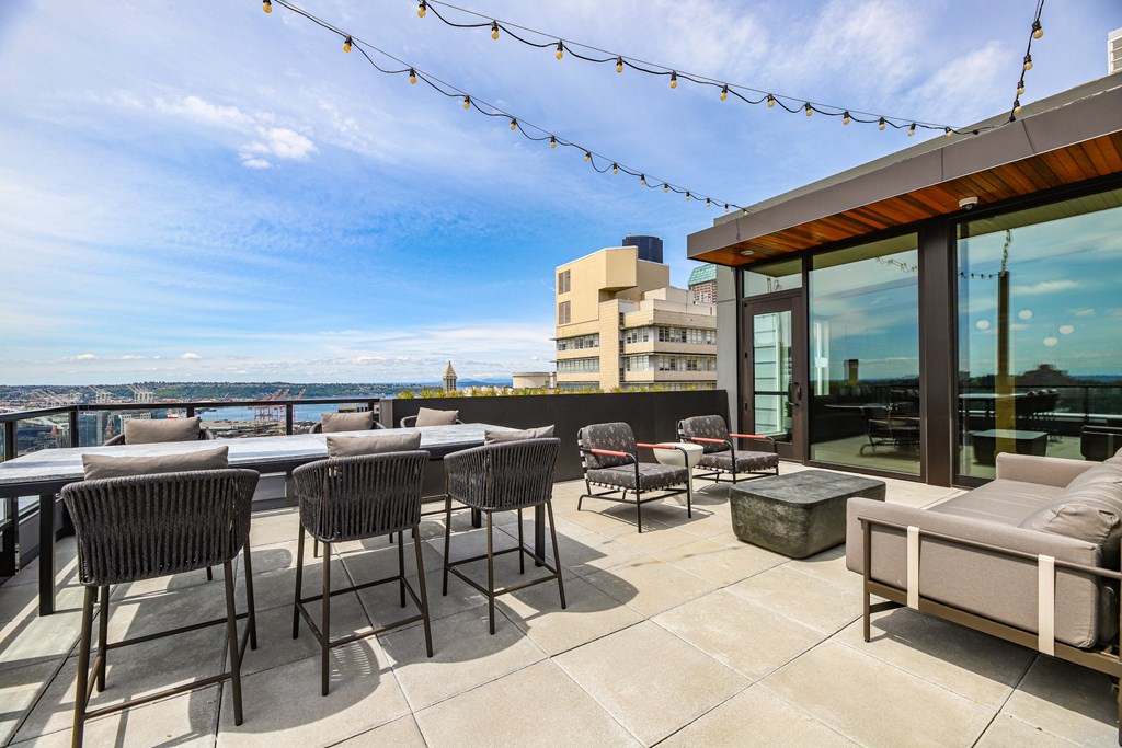 A patio with chairs and a table overlooking a cityscape.