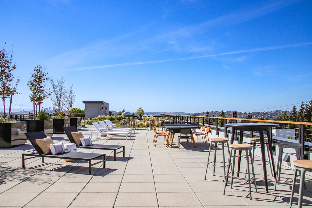 a rooftop patio with tables and chairs and a view of the city