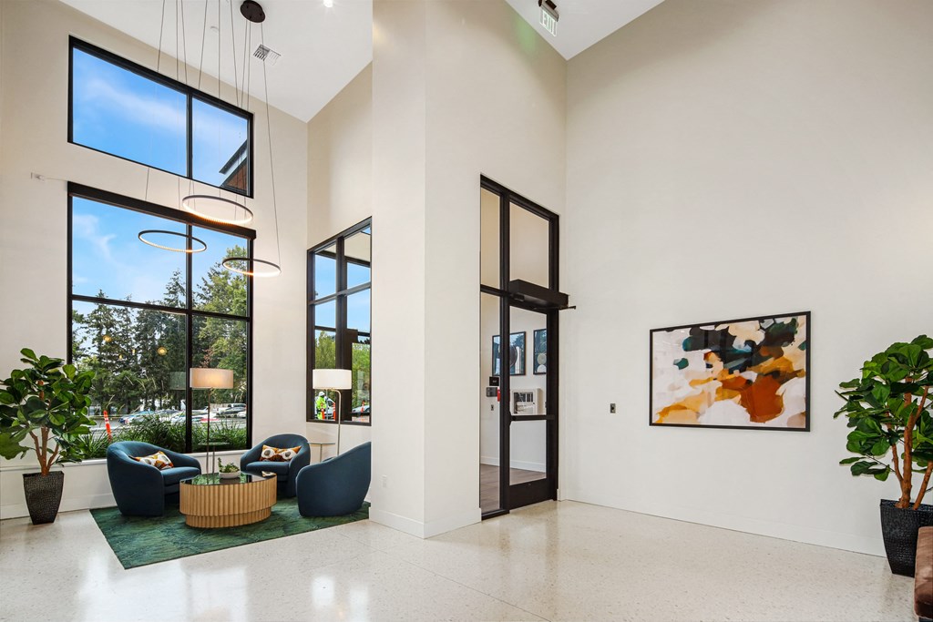 a living room with couches and chairs and large windows
