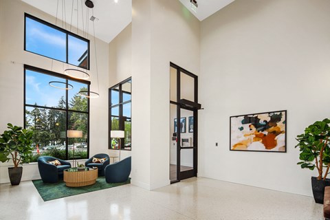 a living room with couches and chairs and large windows