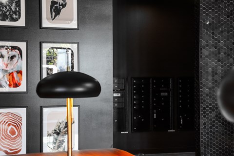 a black wall with pictures and a black chair with a gold lamp