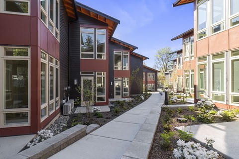 A row of modern houses with a sidewalk in front.