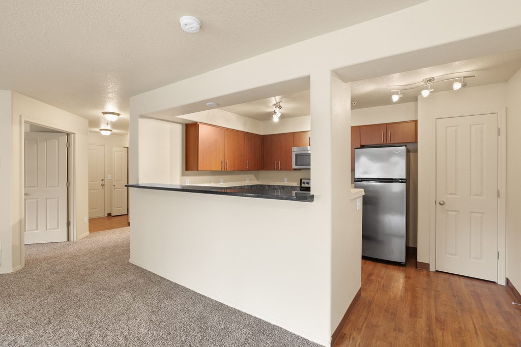 an empty living room and kitchen with a black counter top