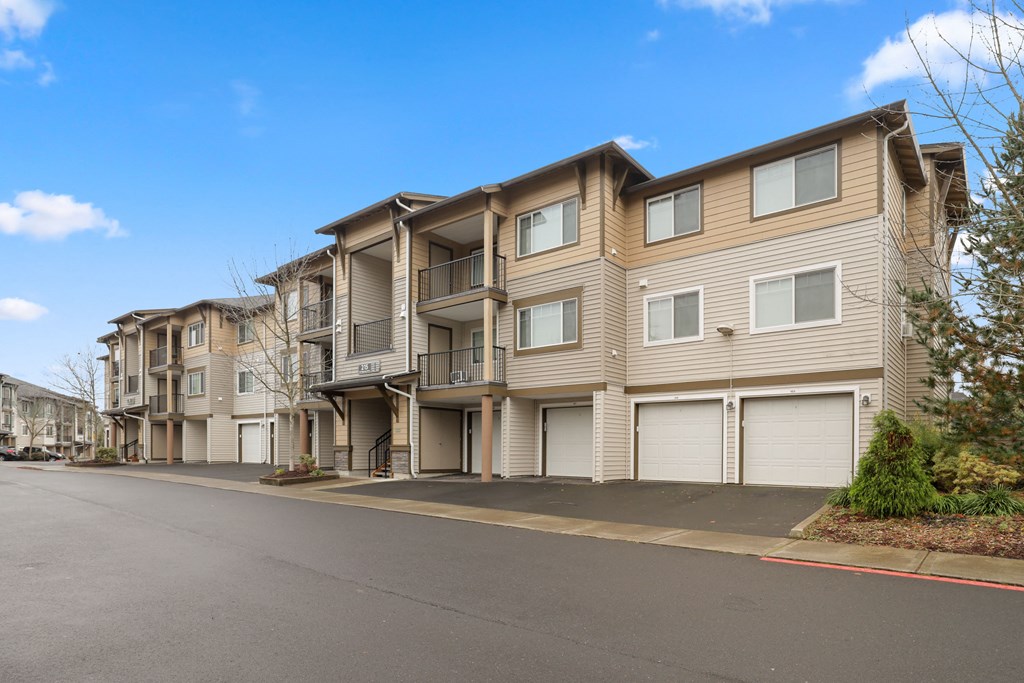 a street view of an apartment building with white garage doors