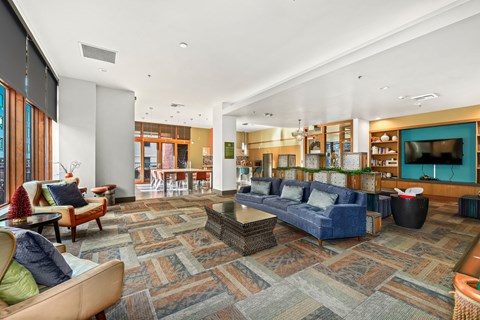 A large room with a patterned carpet and a variety of seating options.