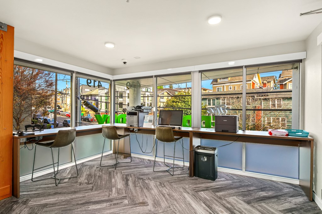 A room with a desk and chairs with a window in the background.