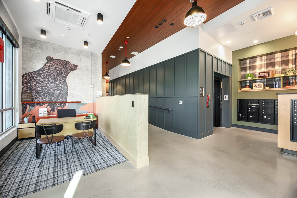 A room with a bear mural on the wall and a kitchen area with a fridge and microwave.