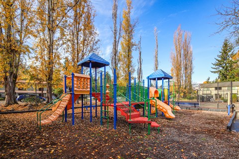 A playground with a red slide and a blue roofed structure.