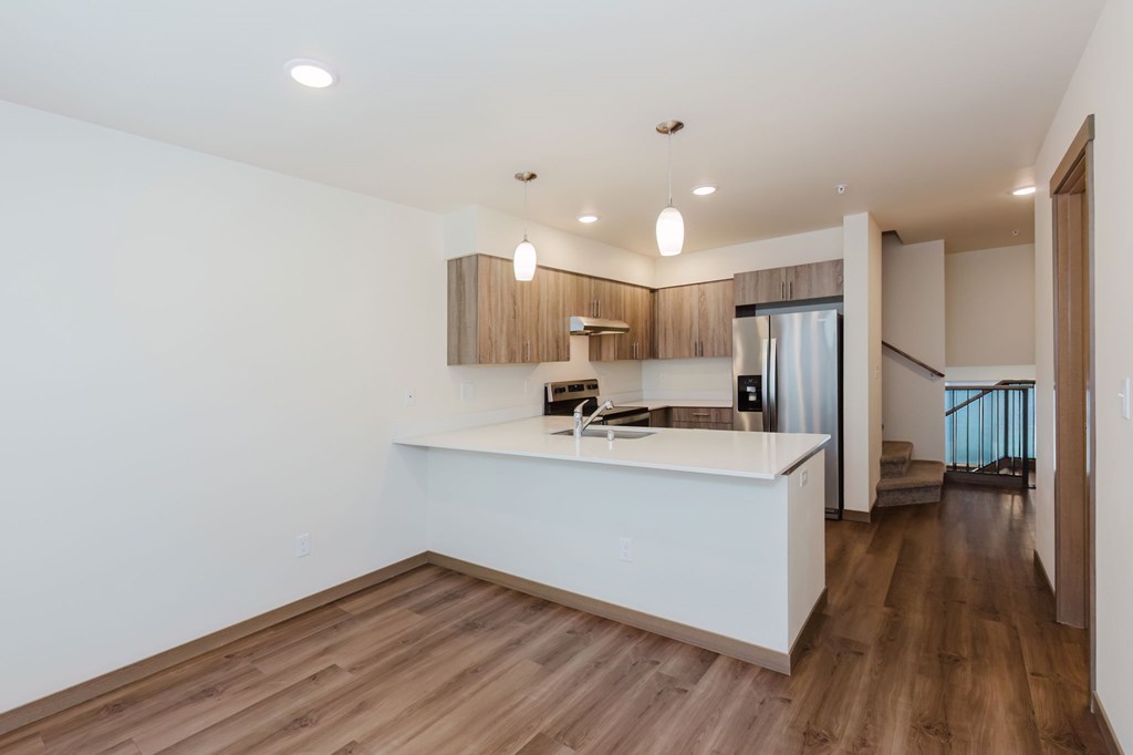 A modern kitchen with wooden floors and white countertops.