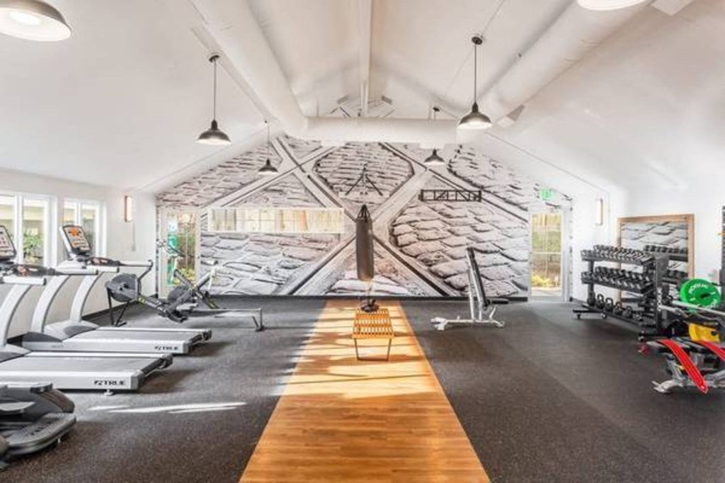 A gym with treadmills, elliptical machines, and a wooden floor.