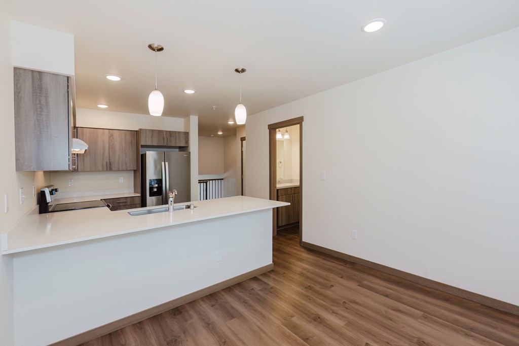 A modern kitchen with a white countertop and wooden flooring.