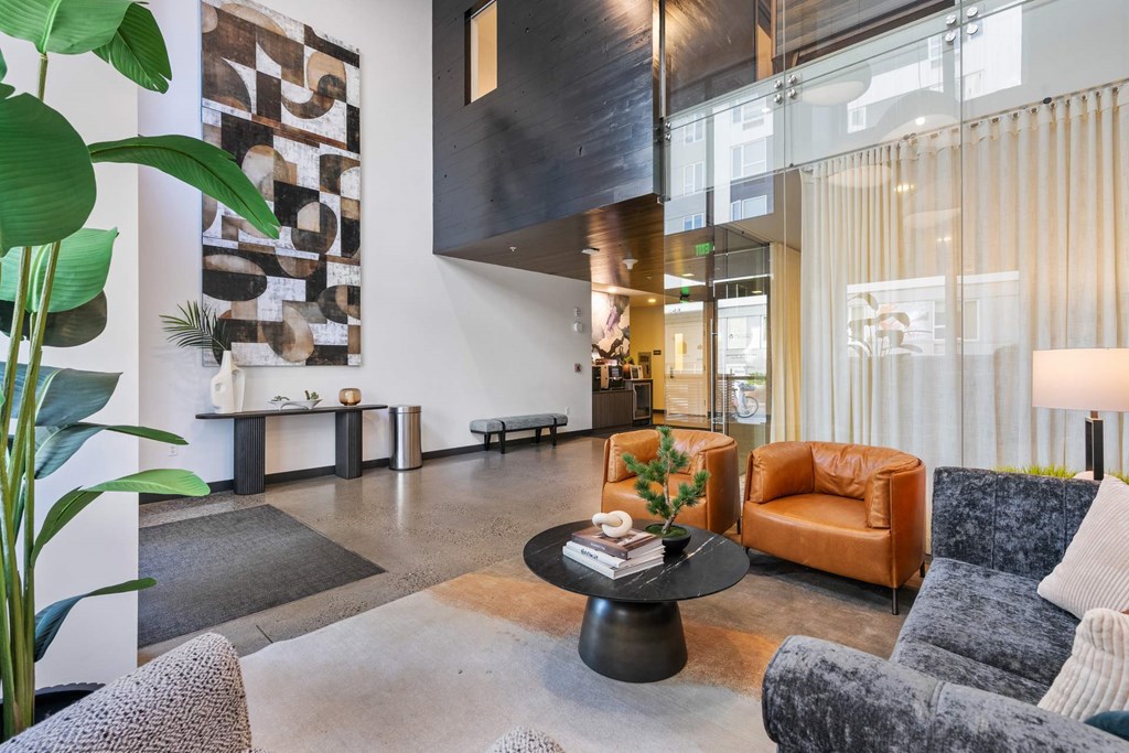 A living room with a grey couch, a black coffee table, and a large painting on the wall.