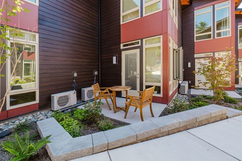 A modern house with a wooden table and chairs outside.
