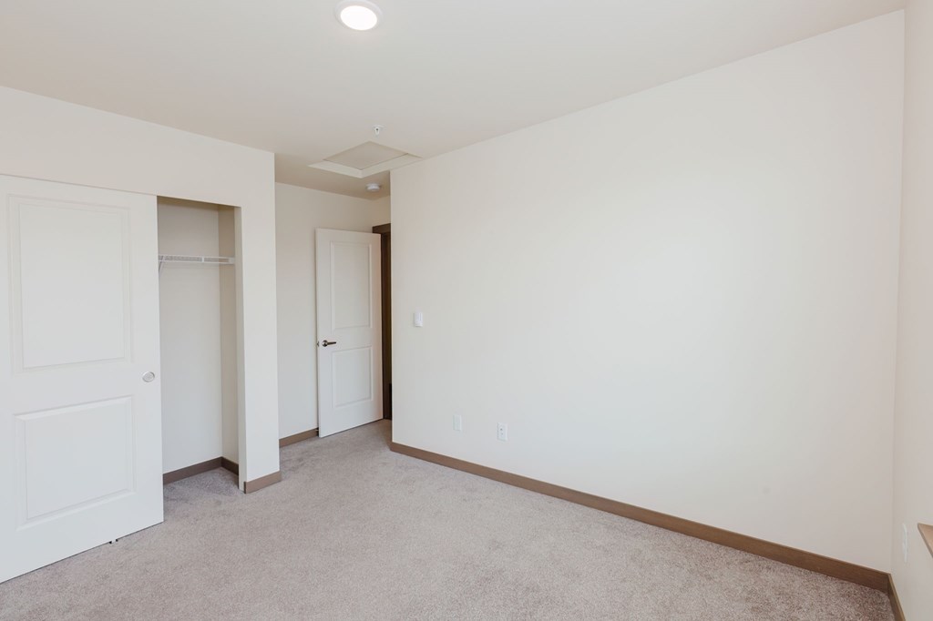 A white room with a carpeted floor and two doors.