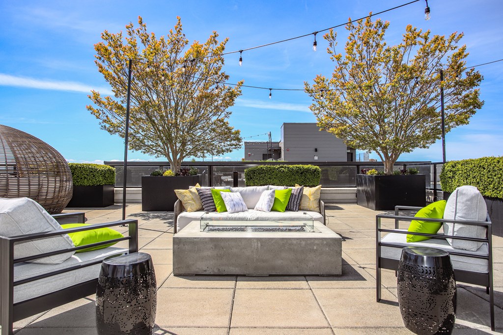 a rooftop patio with couches and chairs and a firepit