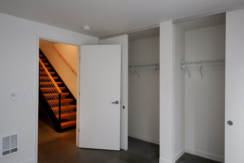 a hallway with a staircase and a closet with a white door