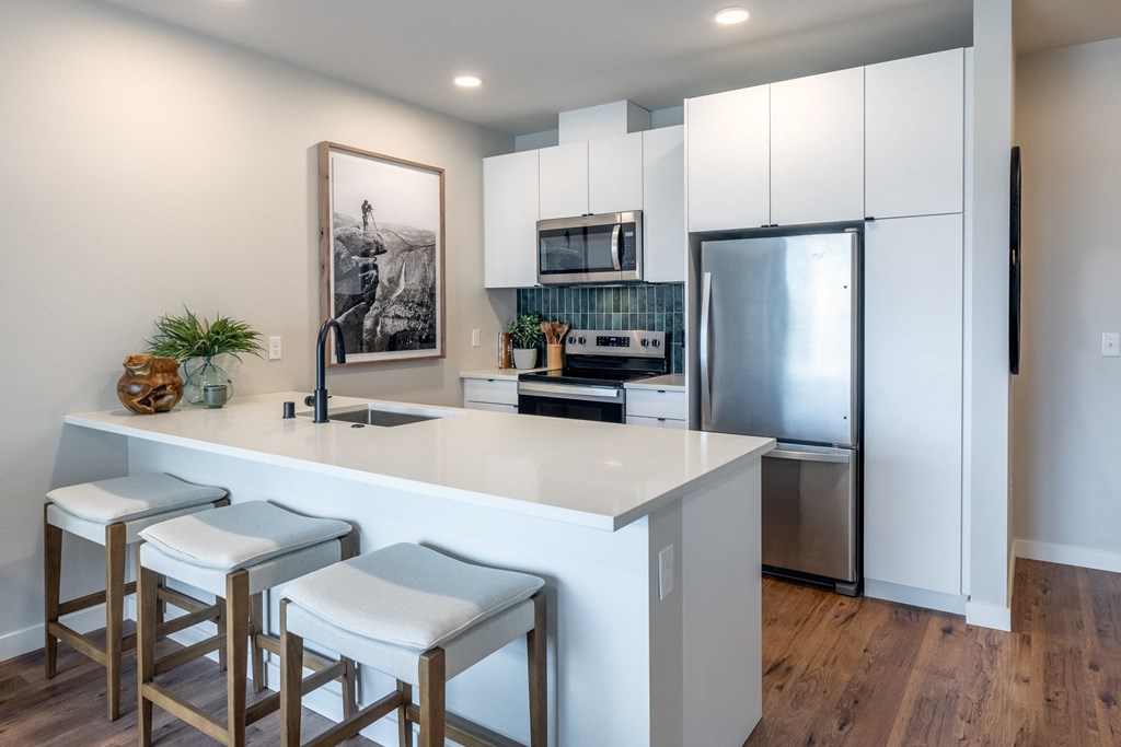 A kitchen with white cabinets and a fridge.