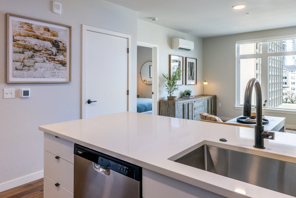 A modern kitchen with a large white countertop and stainless steel appliances.