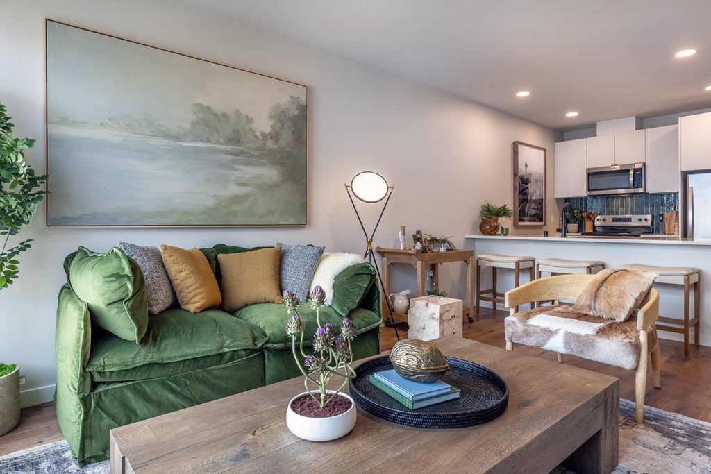 A living room with a green couch, a wooden coffee table, and a painting on the wall.