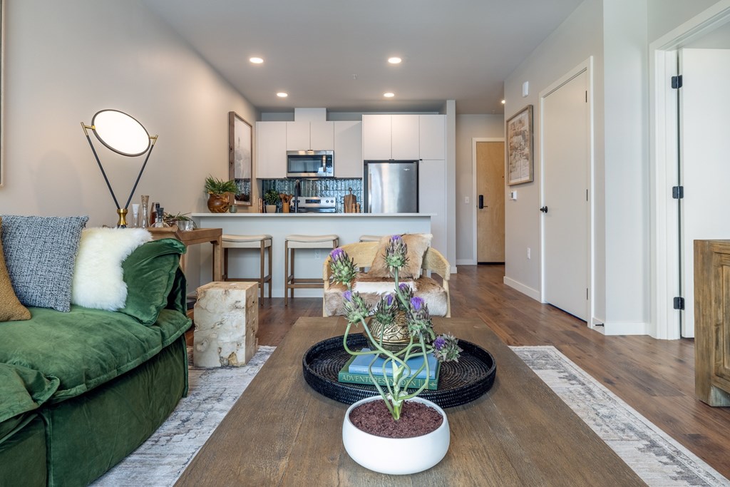 A living room with a green couch and a wooden coffee table with a plant on it.