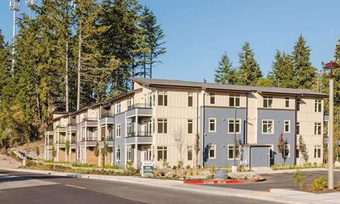 A large building with a grey and blue exterior is surrounded by trees.