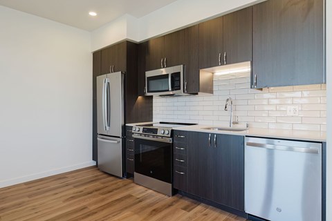 A modern kitchen with dark wood cabinets and stainless steel appliances.