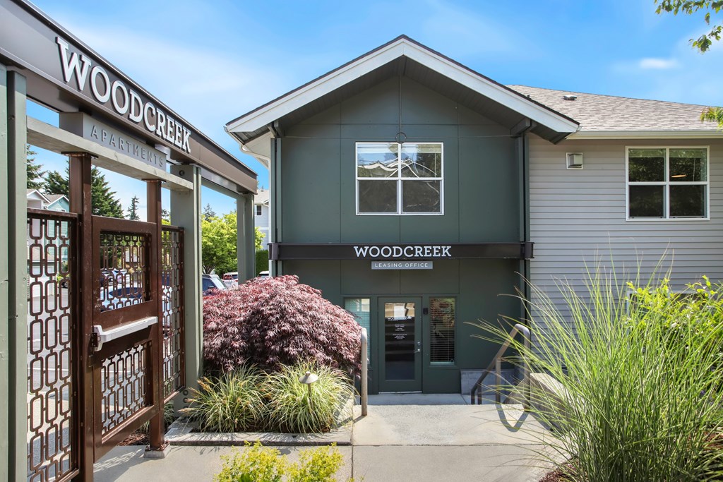 The front of the Woodcreek Apartments building with a sign and a door.