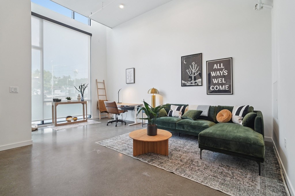 A living room with a green couch and a poster that says "All ways we'll come.".