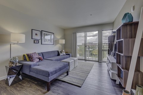 A living room with a grey couch and a wooden floor.
