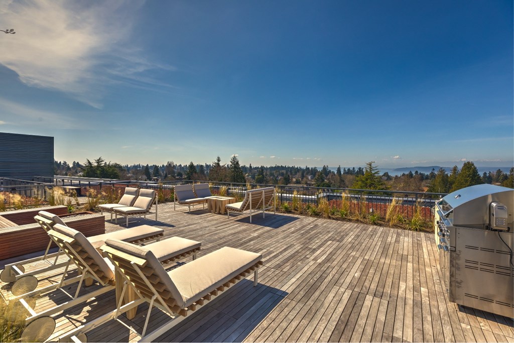 a deck with chairs and a grill on top of a roof