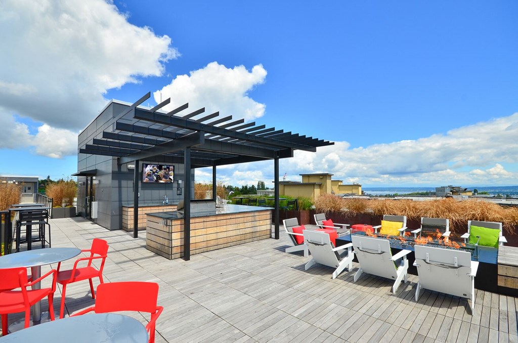 a rooftop deck with tables and chairs and a bar with a tv