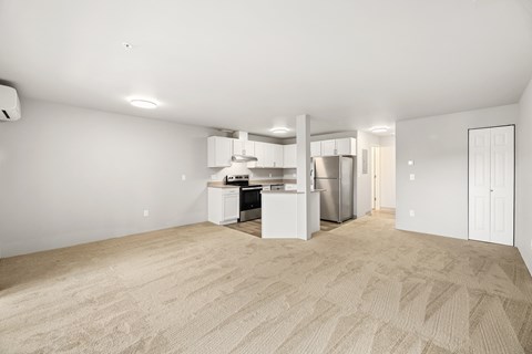 A spacious, empty room with a kitchenette in the corner.