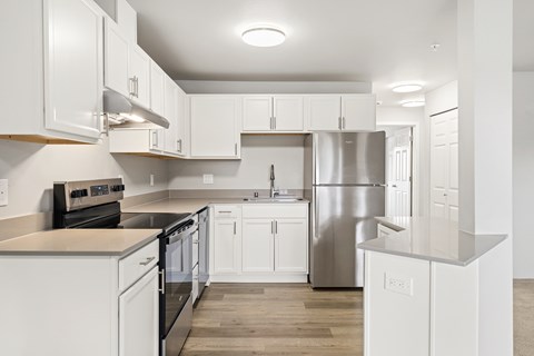 A modern kitchen with white cabinets and stainless steel appliances.