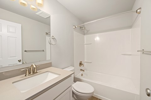 A white bathroom with a toilet, sink, and bathtub.