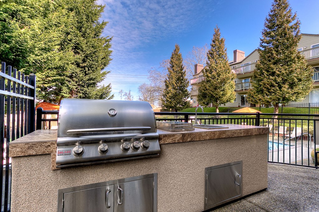 a gas grill on a counter top in a backyard with a pool