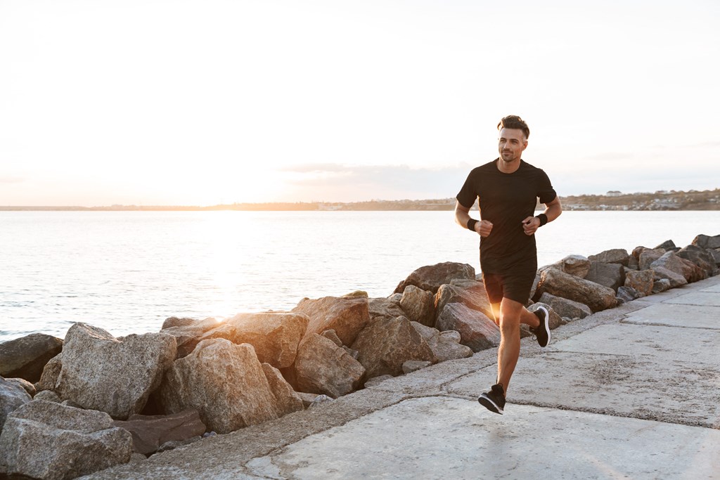 a man running on a sidewalk near a body of water