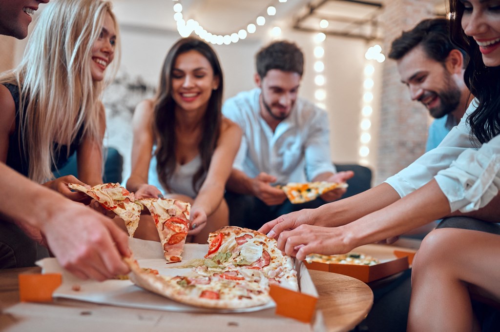 a group of people eating pizza at a party