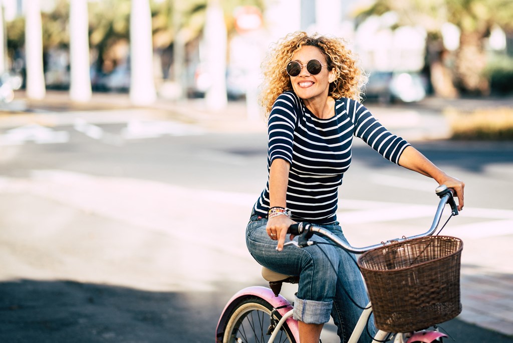 a woman riding a pink bike with a basket